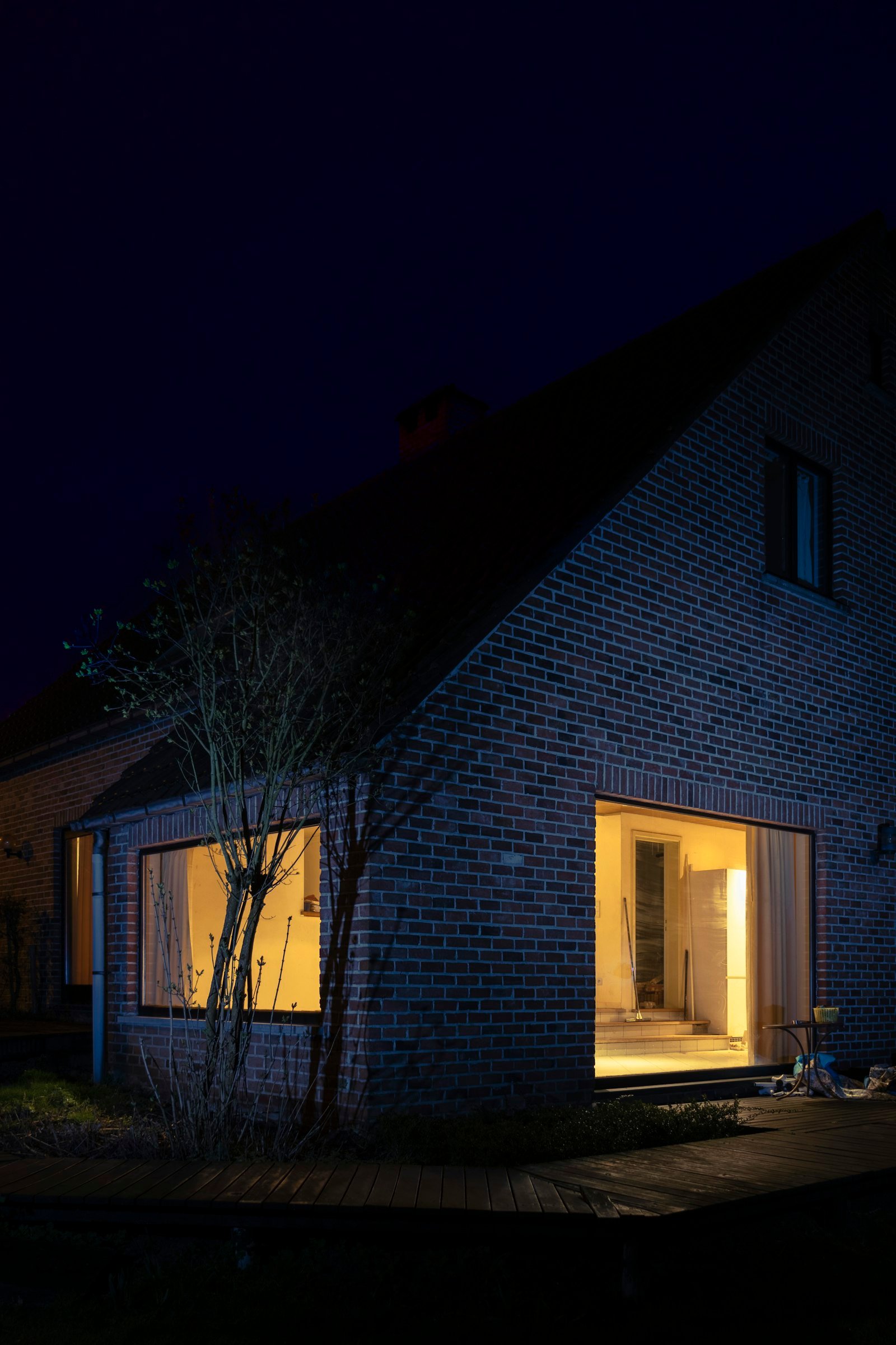 Einfamilienhaus mit Klinkerfassade und Satteldach in der Abenddämmerung, warm beleuchtete Fenster und Holzterrasse — typischer Bestand im Landkreis Regensburg