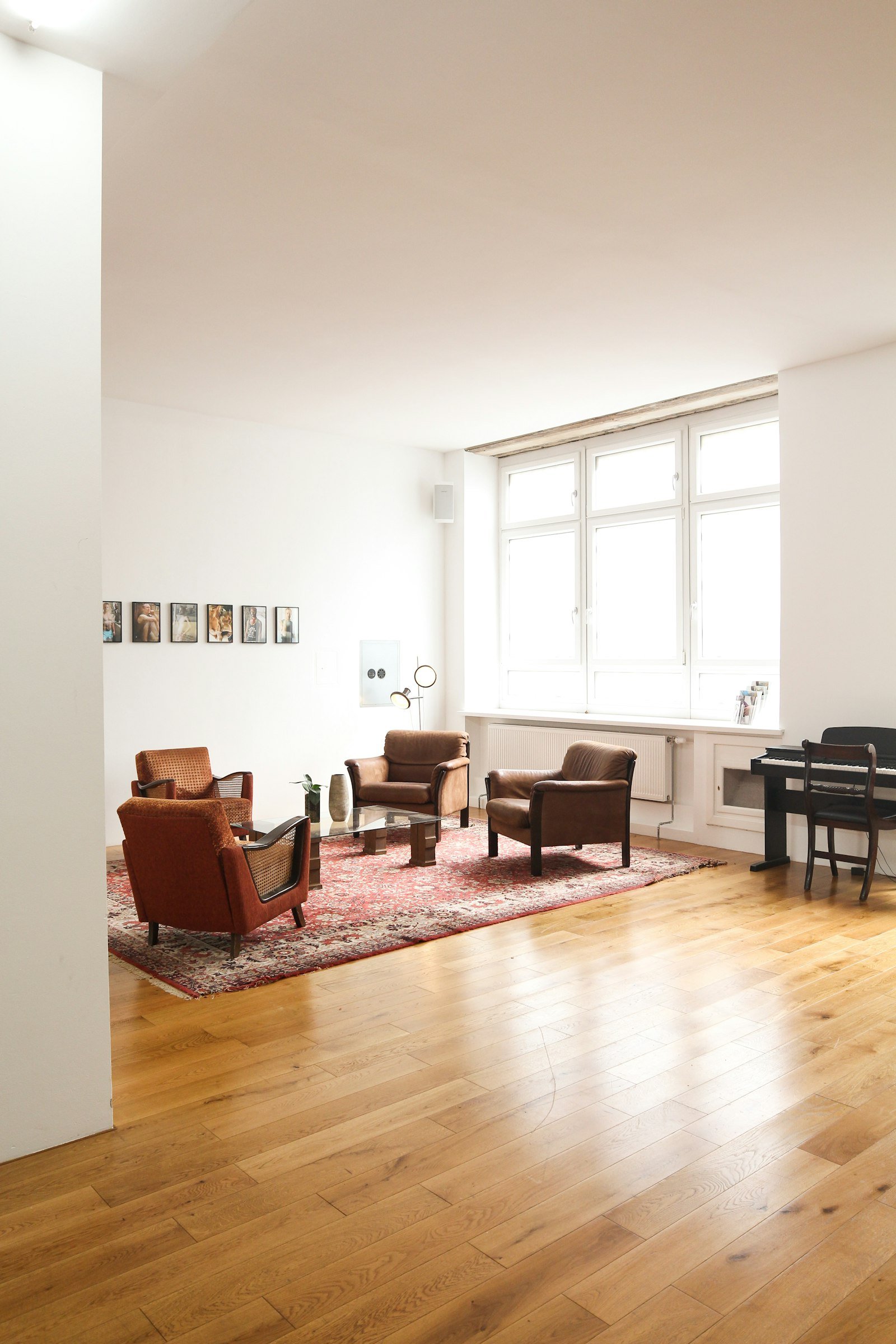 Altbau-Wohnzimmer mit hohen Sprossenfenstern, Eichendielen, Sesseln und Klavier — Wohnungstyp wie in der Regensburger Altstadt